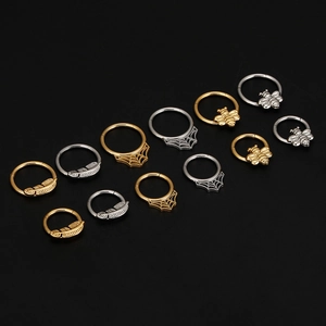 Detalle de aros de septo 16G con diseños de abejas, plumas y telarañas en oro y plata