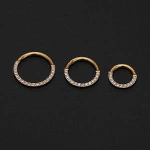 Detailed macro view of three gold hinged clickers with zircon stones in various sizes