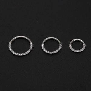 Detailed view of three stainless steel hinged rings with cubic zirconia inlay on black background
