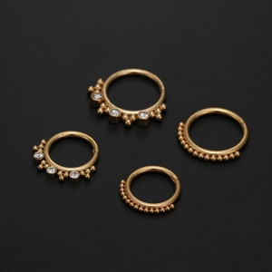 Macro detail of four gold 316L stainless steel clicker rings with zircon and bead accents