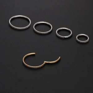 Detailed macro view of 316L stainless steel hinged rings with cubic zirconia in gold and silver