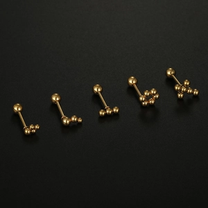 Macro detail of five minimalist gold sphere ear studs in various geometric patterns