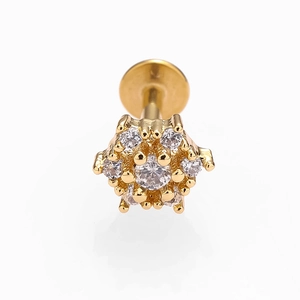 Détail d'un piercing labret doré en forme de fleur avec zircon blanc et base plate