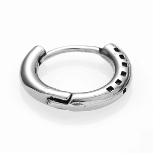 Macro detail of silver stainless steel huggie earring with black square pattern engraving
