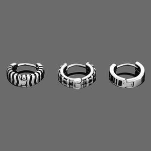 Dettaglio di tre orecchini a cerchio da uomo in argento vintage con motivi geometrici
