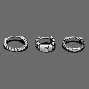 Close-up of vintage titanium steel hoop earrings with engraved industrial and twisted patterns