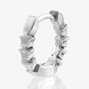 Detailed close-up of a silver sterling silver huggie earring with raised star textures