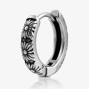 Macro detail of vintage silver hoop earring featuring 3D daisy floral relief carvings