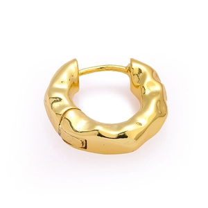 Detail of golden huggie hoop earring featuring a retro textured hammered finish design