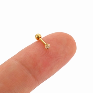 Macro shot showing small gold star ear stud on fingertip for actual size scale