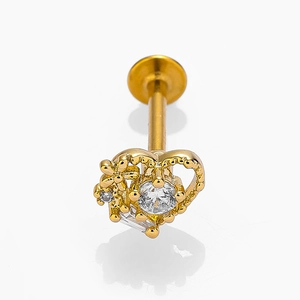Dettaglio macro del piercing labbro a cuore dorato con piccoli fiori e zirconi trasparenti