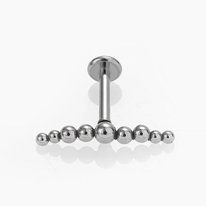 Gros plan sur un piercing labret 16G en acier inoxydable avec design en arc à neuf billes