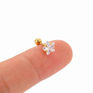 Gold star stud earring with clear zircon inlay and screw ball back on a fingertip