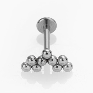 Vista macro de piercing labret de acero 316L con diseño de racimo de bolas pulidas