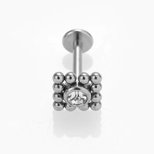 Vue macro d'un piercing en acier inoxydable avec cadre perlé carré et zircon clair