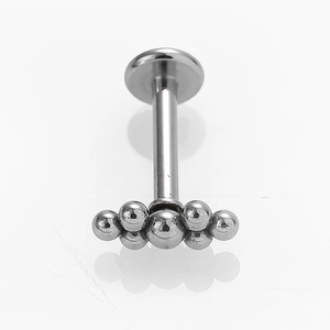 Vista macro de piercing labret en acero 316L con racimo de cuentas en forma de abanico