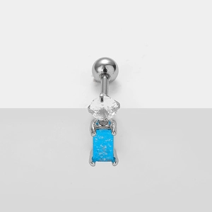 Macro detail of silver stainless steel navel piercing with sparkling blue rectangular gem