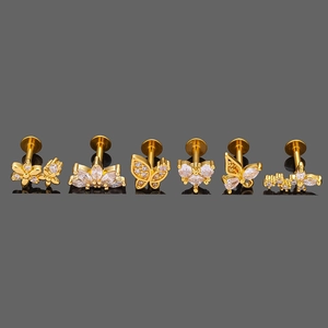 Détail de six piercings labret en acier 316L doré avec motifs papillon et cœur en zircon