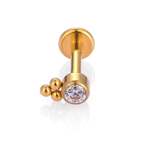Detailed close-up of a gold labret stud with a round zircon and triple bead accents