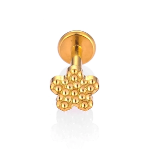 Detailed macro view of golden five-petal flower labret stud with granulation texture