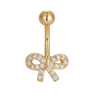Close-up of golden navel ring with crystal-studded bow pendant on a white background