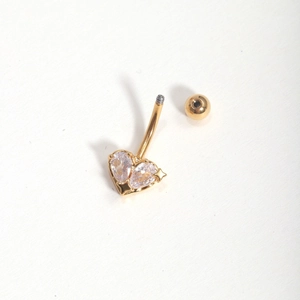 Detailed view of heart-shaped belly ring with gold plating and sparkling zircon stones