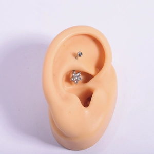 316L stainless steel curved barbell ear stud featuring a zircon flower design on a silicone ear