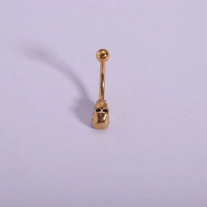 Close-up of golden 316L stainless steel navel piercing with gothic skull design