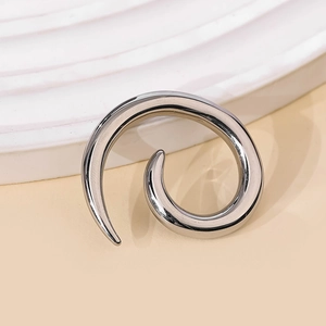 Poids d'oreille spirale en acier poli sur un fond texturé au style minimaliste