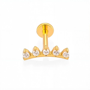 Detail van gouden labret met vijf heldere zirkoonstenen in een gebogen zetting