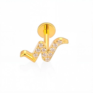 Detail van G23 titanium gouden labret piercing met letter W en witte zirkoon