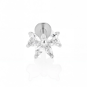 Détail macro du piercing en acier avec nœud en zircones marquises et fond plat