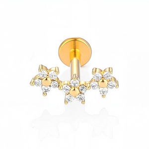 Detailed macro view of gold-plated flower labret piercing with clear cubic zirconia