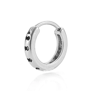 Macro-opname van zilveren huggie oorbel met gepolijste finish en berenpatroon