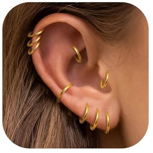 Close-up of multiple G23 titanium gold seamless hoops worn on various ear piercings