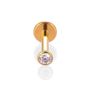 Vue macro d'un piercing labret en titane doré avec zircon rond serti en clos brillant