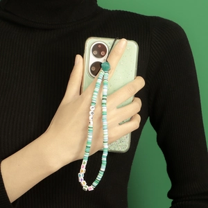 Dettaglio macro del laccio per telefono con perline fatte a mano e scritta LOVE su verde