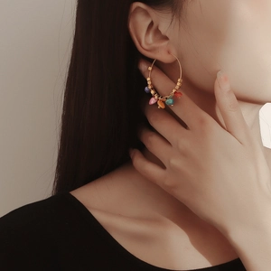 Close-up of bohemian gold hoop earring with colorful turquoise beads on model ear
