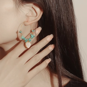 Bohemian gold hoop earrings with turquoise beads and heart pendant on a model