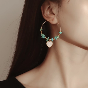 Close-up of bohemian hoop earrings with turquoise beads and heart-shaped shell pendant