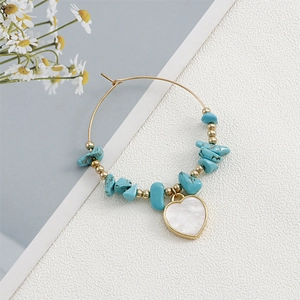 Detail of bohemian gold hoop earring with turquoise beads and shell heart pendant
