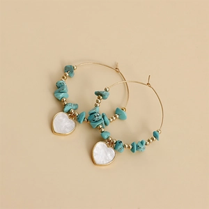 Macro detail of bohemian gold hoop earrings with turquoise stones and heart pendants