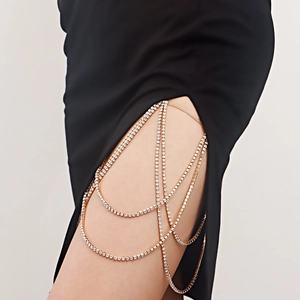 Detail of layered gold leg chain with sparkling white rhinestones on black silk dress