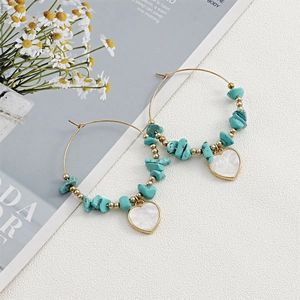 Detail of bohemian gold hoop earrings with turquoise stones and heart shell pendant