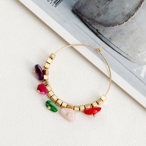 Detail of bohemian gold hoop earrings with colorful turquoise stones and cubic beads