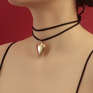 Primer plano de una gargantilla de terciopelo negro con colgante de corazón dorado en una modelo