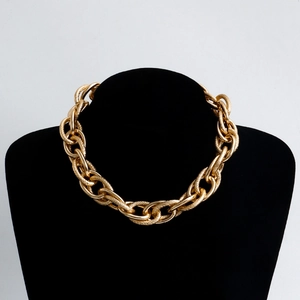 Macro detail of chunky gold chain necklace with textured links on black bust display