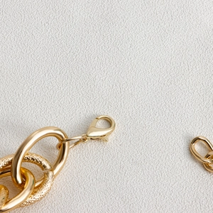 Detailed close-up of golden chunky chain necklace featuring lobster clasp and hammered rings