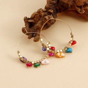 Detail view of colorful bohemian hoop earrings with multi-color stones on wood branch