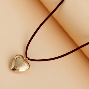 Detalle macro del colgante de corazón de oro pulido con cordón de terciopelo y metal